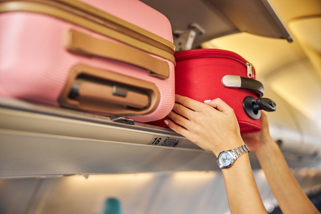 Hands place luggage in the trash on the plane.